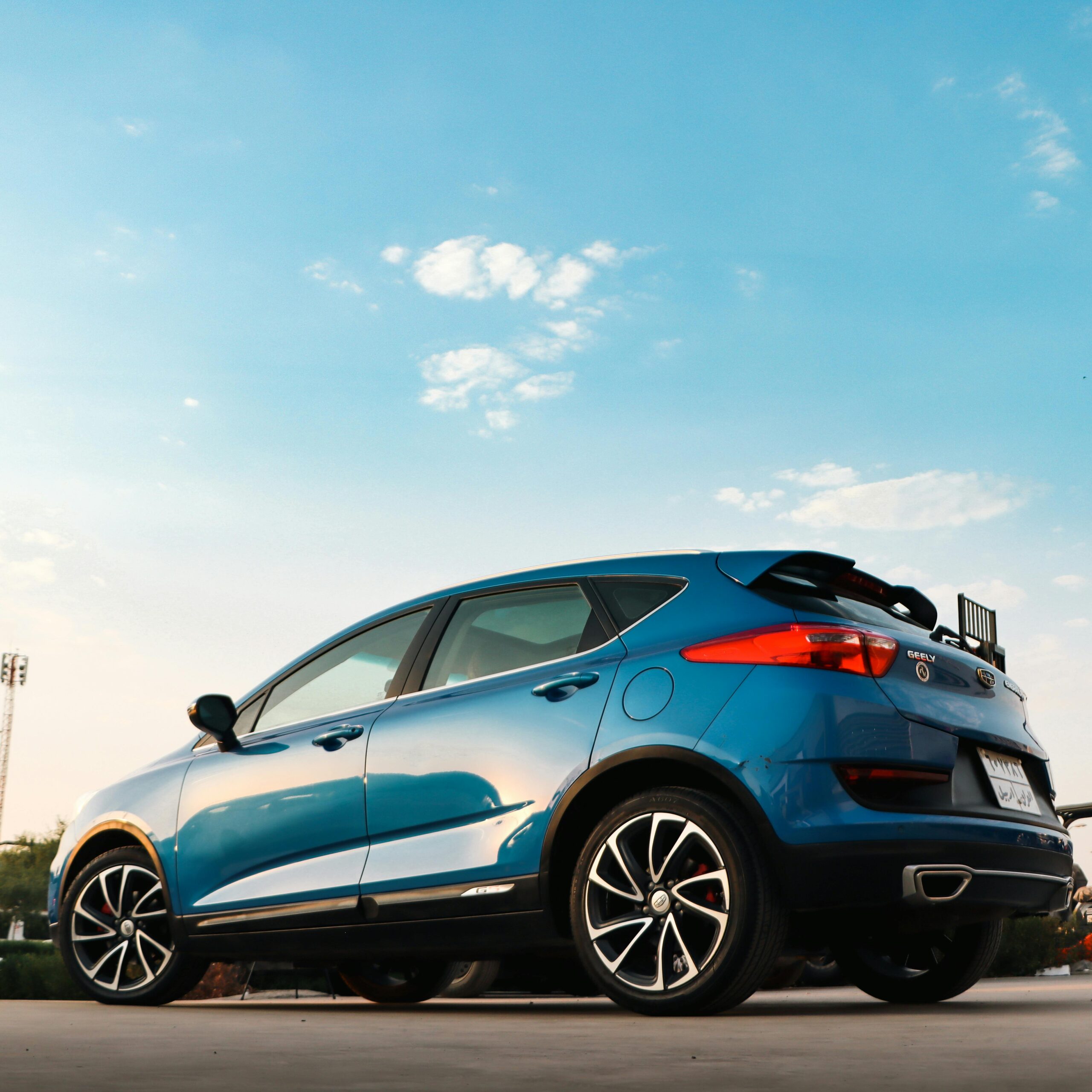 A stylish blue car parked with a vibrant sky background showcasing modern automotive design.