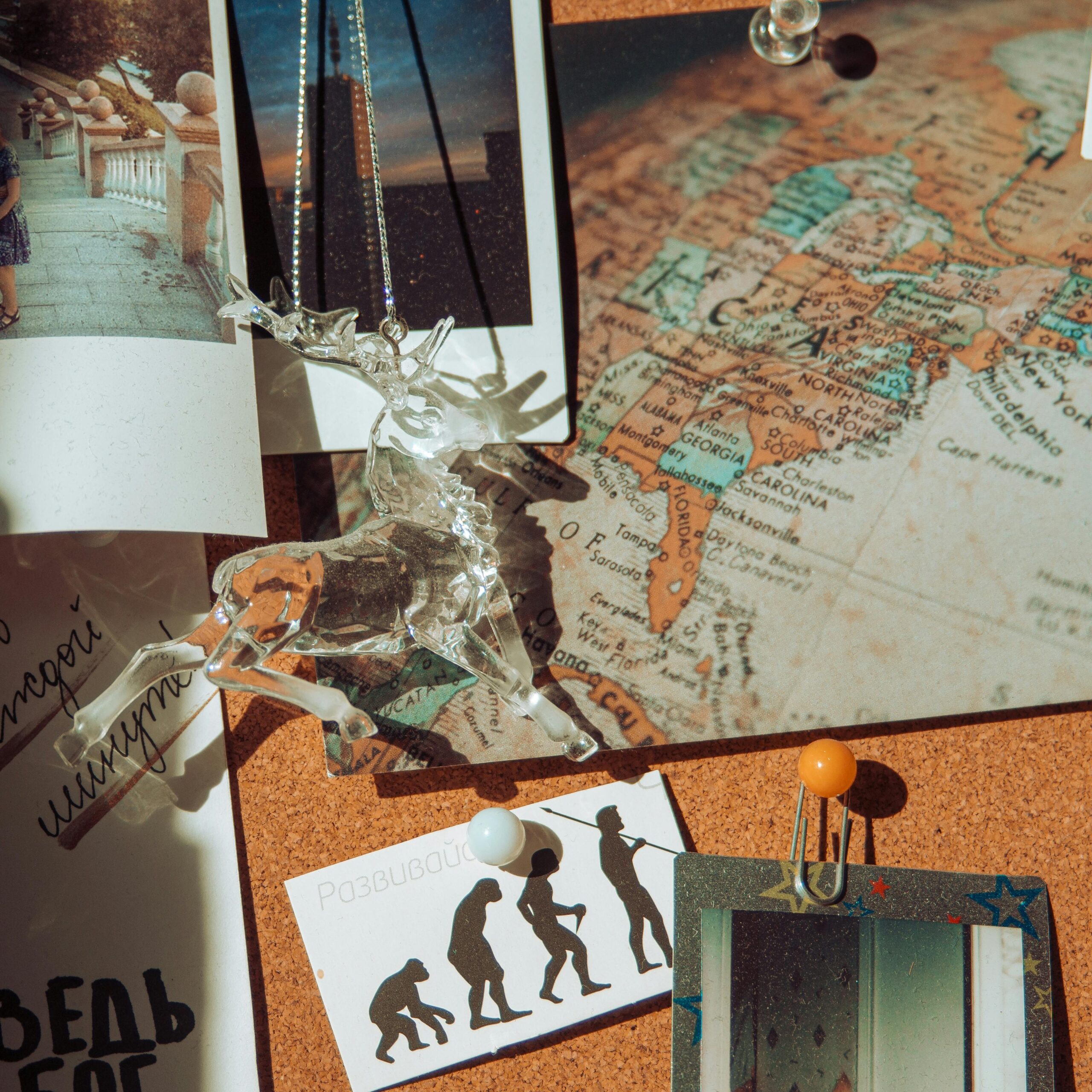 A detailed view of a bulletin board featuring a glass reindeer ornament and a pinned travel map.